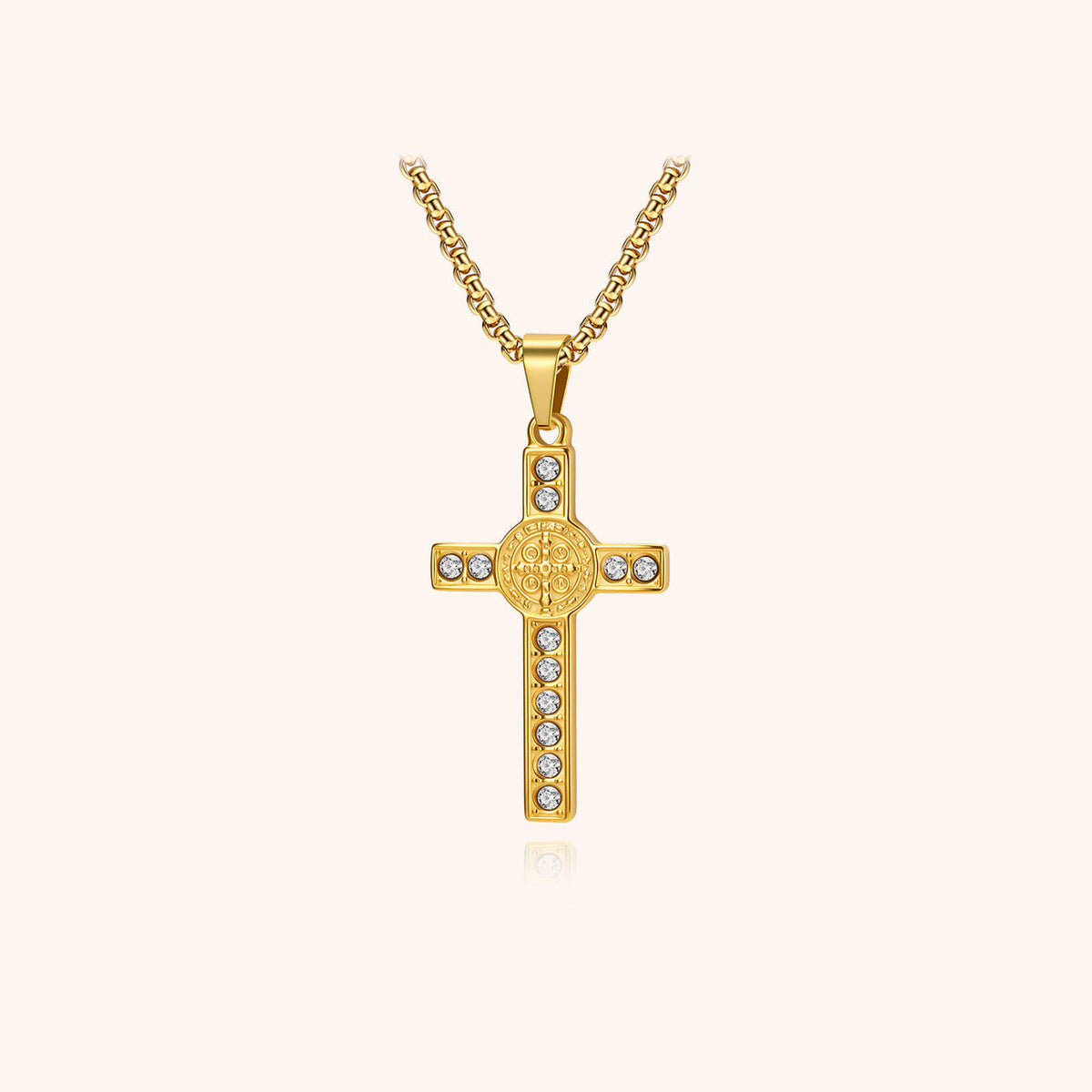 Gold-colored cross pendant with a central engraved medal and clear decorative details, hanging from a chain.