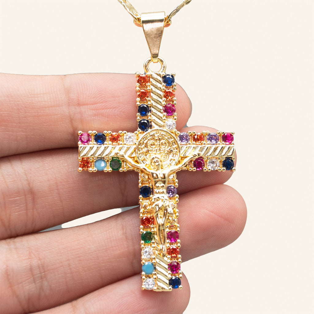 Crucifijo multicolor de San Benito en la mano para mostrar su tamaño