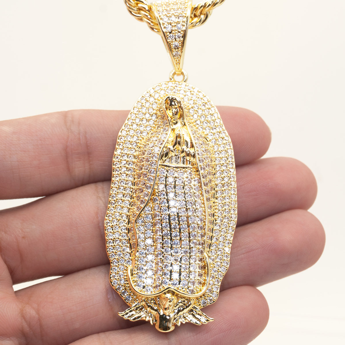 Dije de la Virgen de Guadalupe en la mano para mostrar su tamaño